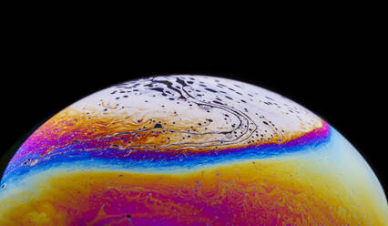 Panoramic view of closeup bubble textured backdrop representing colorful planet with wavy lines on round shaped surface on black background - ADSF22783