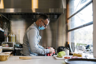 Kellner mit Gesichtsschutzmaske bei der Arbeit im Restaurant - EGAF02310