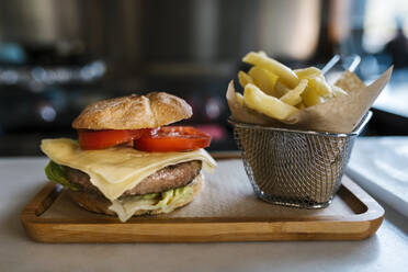 Burger und Pommes frites auf einem Holztablett im Restaurant - EGAF02314