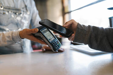 Customer using smart phone for online payment at a bar - EGAF02321