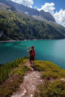 Man photographing by daughters while standing on mountain at Zillertal, Austria - GAF00181