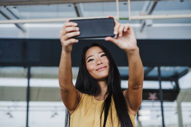 Geschäftsfrau nimmt Selfie von Smartphone in Büro-Cafeteria - EBBF03358