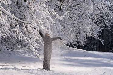 Junge Frau genießt den Winter unter einem verschneiten Baum - LBF03505