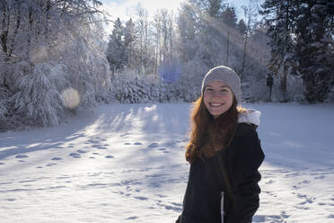 Lächelnde schöne Frau im Schnee stehend an einem sonnigen Tag - LBF03511