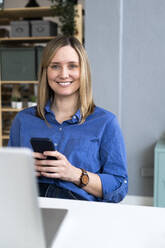 Lächelnde blonde Frau mit Mobiltelefon - GIOF12484