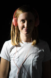 Smiling woman with headphones against black background - GIOF12511