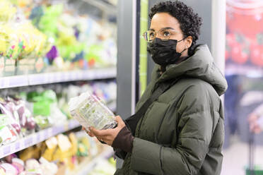 Woman wearing padded jacket shopping in supermarket during COVID-19 - VYF00592