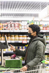 Junge Frau beim Bezahlen im Supermarkt - VYF00593