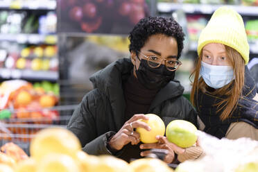 Freundinnen beim Obstkauf im Supermarkt während COVID-19 - VYF00598