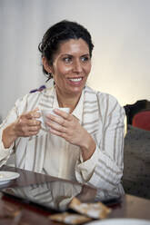 Smiling woman with coffee cup at cafeteria - VEGF04220