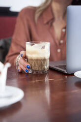 Geschäftsfrau hält Kaffeetasse am Tisch - VEGF04229