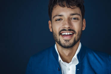 Lächelnder junger Mann vor blauem Hintergrund - JOSEF04015