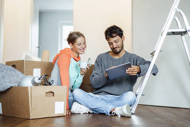 Young couple discussing over digital tablet at new home - JOSEF04021