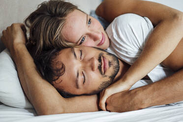 Young couple lying on bed while looking away - JOSEF04059