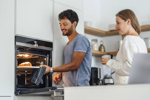 Mann mit Freundin bei der Zubereitung von Croissants in der Küche zu Hause - JOSEF04088