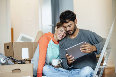 Young couple using digital tablet at new home - JOSEF04106