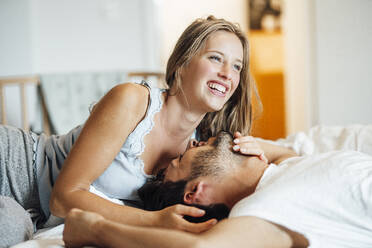 Cheerful young couple lying on bed at home - JOSEF04119