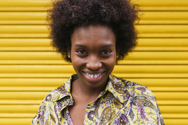 Lächelnde Frau vor einem gelben Fensterladen - JRVF00425