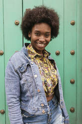 Mid adult woman wearing denim jacket standing in front of wall - JRVF00431