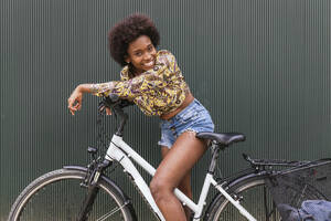 Schöne Frau lehnt sich an Fahrrad an Wand - JRVF00442