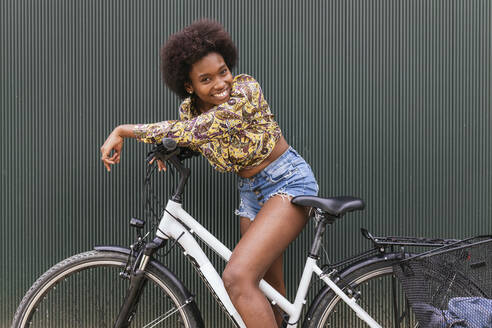 Beautiful woman leaning on bicycle by wall - JRVF00442