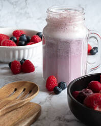 Refreshing berry smoothie in glass cup placed on table with raspberries and blueberries for healthy breakfast - ADSF22866