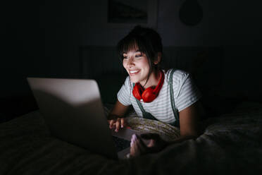 Lächelnde Frau beim Betrachten eines Films in der Dunkelkammer - TCEF01767