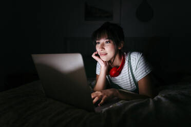 Beautiful woman with hand on chin watching movie in darkroom - TCEF01768