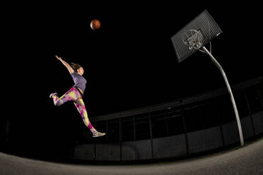 Junge Frau springt beim nächtlichen Basketballspielen - STSF02931