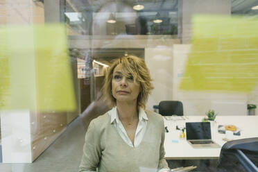 Businesswoman looking at adhesive notes in coworking office - XLGF01487