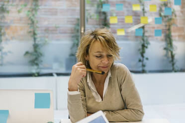 Nachdenkliche Geschäftsfrau sitzt am Schreibtisch in einem Coworking-Büro - XLGF01498
