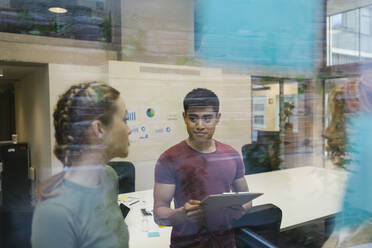 Male and female professionals discussing at office seen through glass - XLGF01520