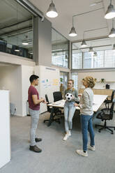 Männliche und weibliche Unternehmer spielen Fußball im Coworking-Büro - XLGF01528