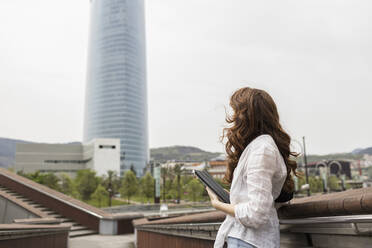 Frau stehend mit digitalem Tablet in der Stadt - MTBF00973