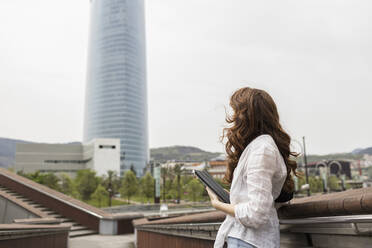 Woman standing with digital tablet in city - MTBF00973