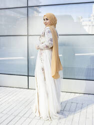 Junge modische Frau mit Hidschab und Kleid auf dem Fußweg stehend - JCCMF01919