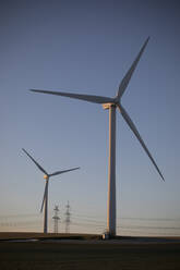 Germany, North Rhine Westphalia, Grevenbroich, Wind turbines and electricity pylons at sunset - JATF01303