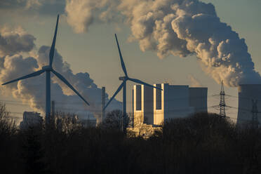 Deutschland, Nordrhein-Westfalen, Neurath, Windräder und Braunkohlekraftwerk bei Sonnenuntergang - JATF01316