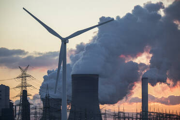 Germany, North Rhine Westphalia, Niederaussem, Wind turbines and lignite power station at sunset - JATF01317