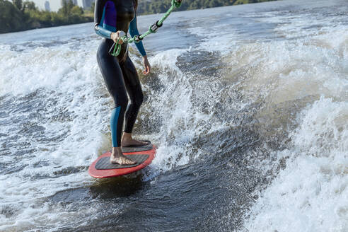 Niedriger Ausschnitt einer Frau beim Wakesurfen im Fluss Moskva - KNTF06238