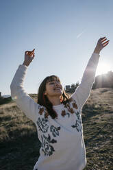 Happy woman with arms raised spending leisure time on mountain - TCEF01786