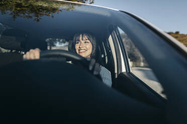 Junge Frau am Steuer eines Autos durch die Windschutzscheibe gesehen - TCEF01790