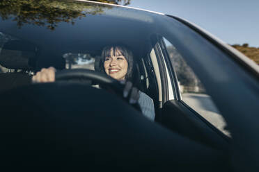 Young woman driving car seen through windshield - TCEF01790