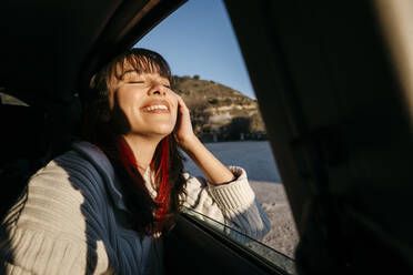 Happy woman with eyes closed travel in car - TCEF01792