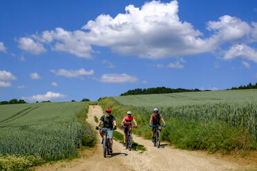 Germany, Bavaria, Upper Palatinate, Three mature adults cycling in rural scenery - LBF03516