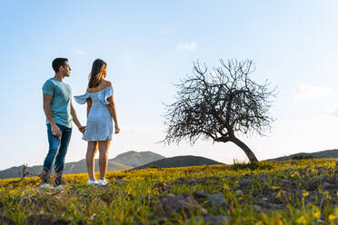 Couple looking at view while standing together on grass - MIMFF00697