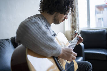Männlicher Musiker spielt zu Hause Gitarre - FBAF01817