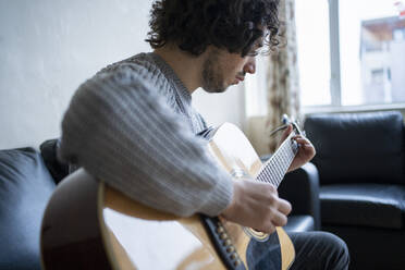 Male musician playing guitar at home - FBAF01817