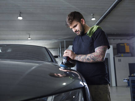 Technician polishing car with equipment at garage - CVF01720