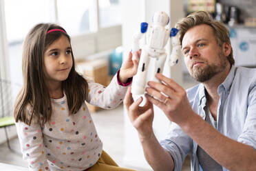 Father holding robot toy by daughter at home - JOSEF04133